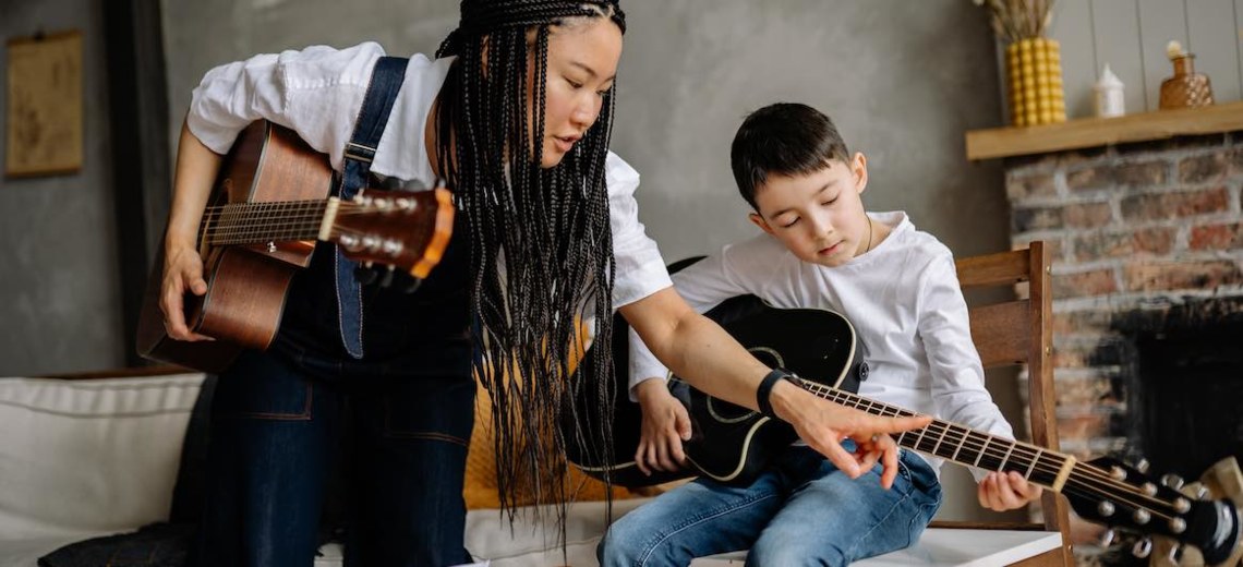 woman teaching guitar to a young student